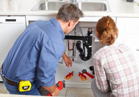 plumber and customer at kitchen sink 